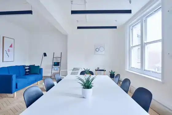 Salle de réunion minimaliste, table blanche et canapé bleu